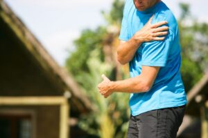 A man holding his shoulder experiencing discomfort from a rotator cuff injury