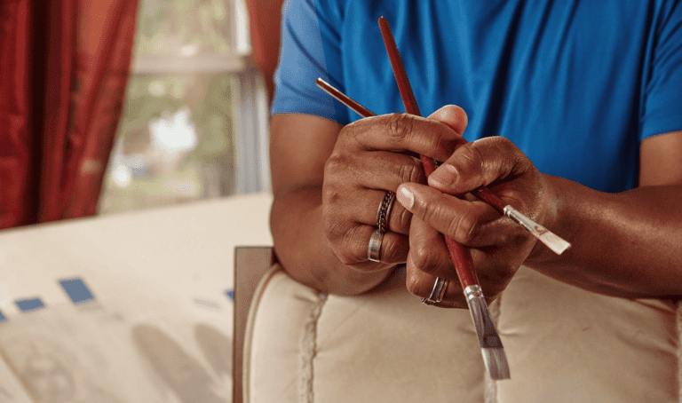 A man holding two paint brushes, symbolizing hand pain treatments in Greenwood, IN