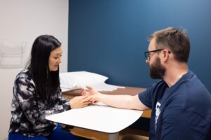 At Forte Sports Medicine, a man and Toni Lin sit at a table discussing Flexor Tendon Injury