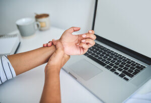 woman on laptop struggling with carpal tunnel
