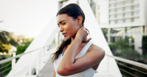 Runner, neck pain and injury or ache with workout, strain and exercise in city. Woman, athlete and stretching with accident, sore or bruise with inflammation and outdoor training for fitness in town